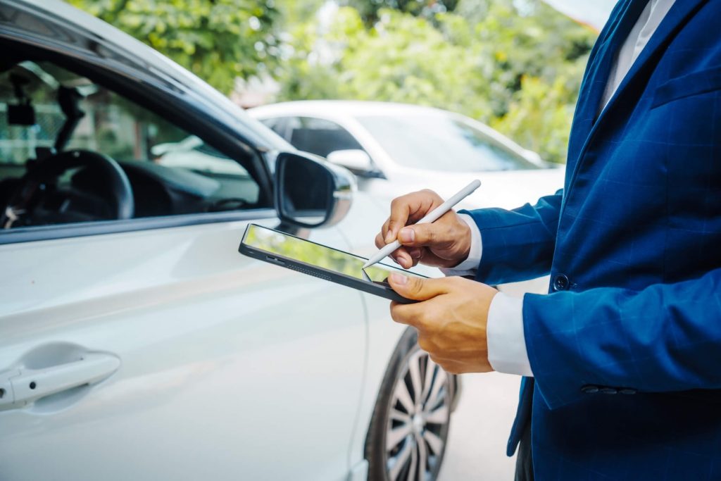 businessman in suit and car auto insurance agent assess car damage, discussing deductible, claims, coverage options comprehensive and collision insurance, completing necessary forms and appraisals.