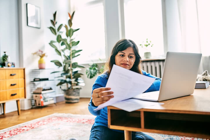 Woman calculating household expenditures finances at home. Woman looking at bills while doing home finances.